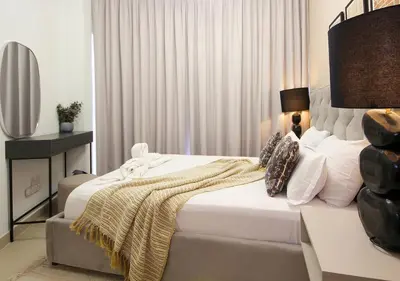 a bedroom with a bed and a table with a lamp at Stylish 2BR in Bellevue Pool, Gym & Burj Views in Dubai