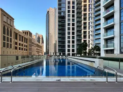 a large swimming pool in a city with tall buildings at Stylish 2BR in Bellevue Pool, Gym & Burj Views in Dubai