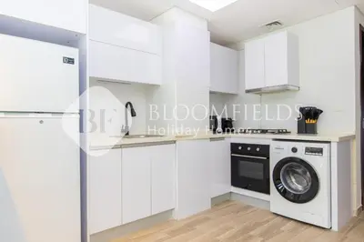 a white kitchen with a washer and dryer at Bloomfields Modern Escape STU In JVC in Dubai