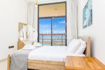 a bedroom with a bed and a table and a window at Bloomfields 1Br The Avenue Suite Bingahtti in Dubai
