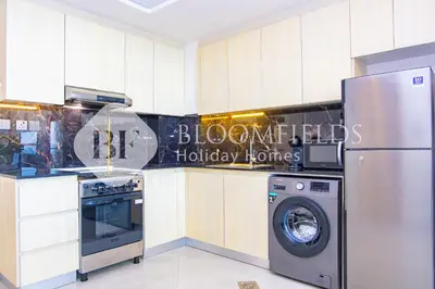 a kitchen with a refrigerator and a washing machine at Bloomfields 1Br The Avenue Suite Bingahtti in Dubai
