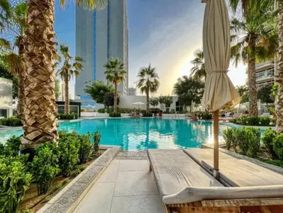 a swimming pool with an umbrella and palm trees at Wonderful Stay At Zaya Hameni - Best Amenities - Unique in JVC - Brand New Luxury Apartments in Dubai