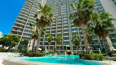 a hotel with palm trees in front of a building at Wonderful Stay At Zaya Hameni - Best Amenities - Unique in JVC - Brand New Luxury Apartments in Dubai