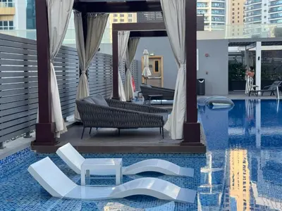 a hotel swimming pool with white chairs in the water at STUDIO ONE Stunning Marina View - TIE in Dubai