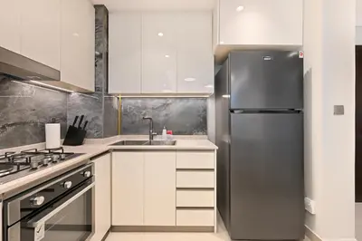 a kitchen with white cabinets and a stainless steel refrigerator at Stunning 1 Bdr Luxury with Burj Khalifa View in Dubai
