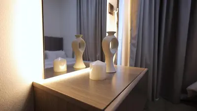 three white vases sitting on a dresser in front of a mirror at 2 Bedroom Elegant Apartment in Dubailand in Dubai