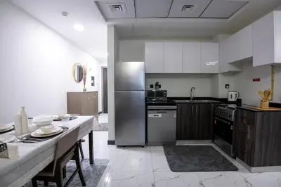 a kitchen with stainless steel appliances and a table at 2 Bedroom Elegant Apartment in Dubailand in Dubai