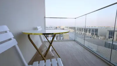 a table and chairs in a room with a balcony at 2 Bedroom Elegant Apartment in Dubailand in Dubai