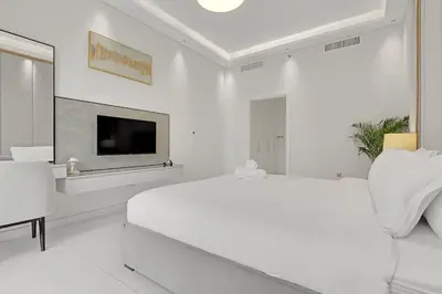 a white bedroom with a large bed and a tv at Spacious 3BR , Balcony & City Views by Bhavan Vacation Homes in Dubai