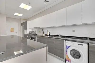 a white kitchen with a washing machine in it at Spacious 3BR , Balcony & City Views by Bhavan Vacation Homes in Dubai