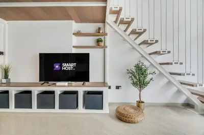 a living room with a tv and a staircase at Luxury Loft with Balcony in JVC, Oxford Terraces 2 in Dubai