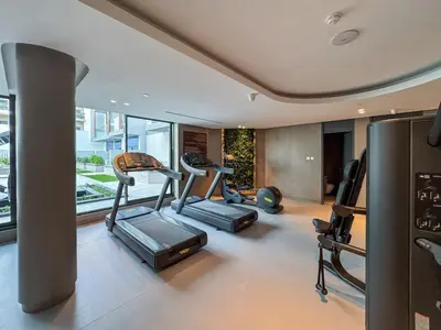 a gym with treadmills and ellipticals in a room at Luxury Loft with Balcony in JVC, Oxford Terraces 2 in Dubai
