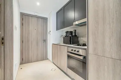 a kitchen with wooden cabinets and a stove at Luxury Loft with Balcony in JVC, Oxford Terraces 2 in Dubai