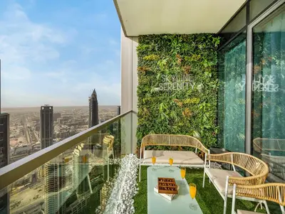 a balcony with a green wall with a table and chairs at Grande Signature 2 Bedroom Apartments I Persian Gulf Views I Free Parking, Gym, Pool, Wi-Fi & PS5 I by Skyline Serenity in Dubai