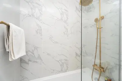 a bathroom with a shower with white marble walls at GuestReady - Fabulous home with Marina Canal views in Dubai