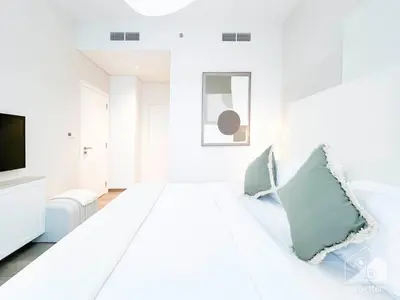 a white room with a bed and a television at Sophisticated 1B Apartment in Belgravia Heights II in Dubai