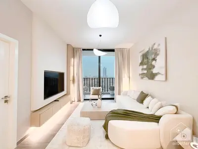 a white living room with a couch and a tv at Sophisticated 1B Apartment in Belgravia Heights II in Dubai