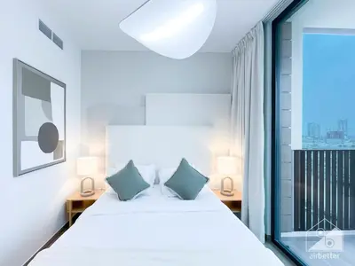 a bedroom with a white bed and a large window at Sophisticated 1B Apartment in Belgravia Heights II in Dubai