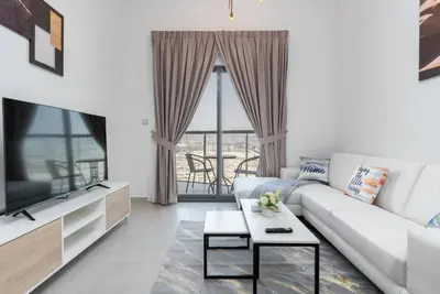 a living room with a white couch and a tv at Delightful 2 Bedrooms In Jumeirah Village Circle in Dubai