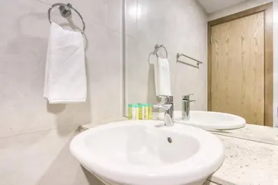 a white bathroom with a sink and a mirror at Serene 2 Bedrooms Apartment in Dubai