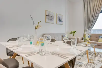 a white dining room table with plates and glasses at Serene 2 Bedrooms Apartment in Dubai