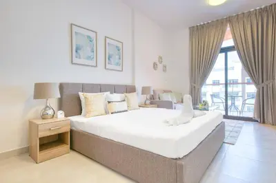 a bedroom with a large bed and a balcony at Posh Studio Apartments in Dubai
