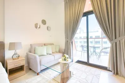 a living room with a couch and a balcony at Posh Studio Apartments in Dubai