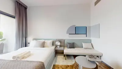a hotel room with two beds and a chair at Mag Eye - Cozy Studio in Meydan in Dubai