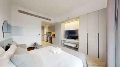 a bedroom with a white bed and a living room at Mag Eye - Cozy Studio in Meydan in Dubai
