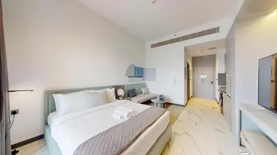 a white bedroom with a large bed and a couch at Mag Eye - Cozy Studio in Meydan in Dubai
