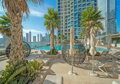 a resort with a pool and palm trees and chairs at Bespoke Holiday Homes - Luxurious Studio in Damac Maison Prive in Dubai