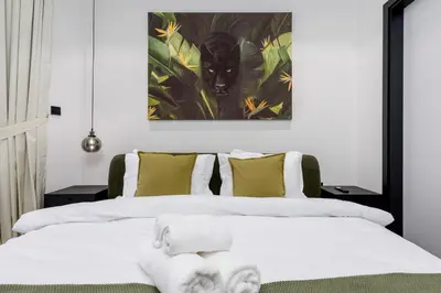 two beds in a bedroom with a cat painting on the wall at Waves - Elegant Waterfront Living in Dubai's Business Bay in Dubai