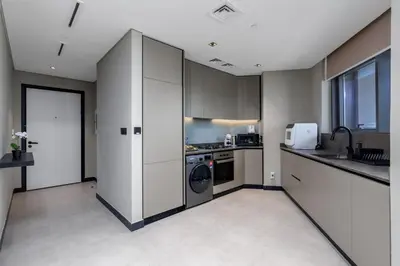 a kitchen with white cabinets and a washer and dryer at Waves - Elegant Waterfront Living in Dubai's Business Bay in Dubai