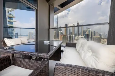 a balcony with a glass table and wicker chairs at Waves - Elegant Waterfront Living in Dubai's Business Bay in Dubai