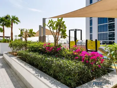 a garden with pink flowers and palm trees at Winter Bliss Studio Azizi Riviera 9 Pool View in Dubai