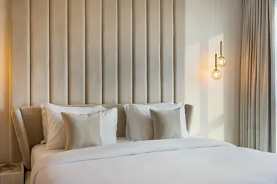 a bed with white sheets and pillows in a room at Durrani Homes - Modern Living 3br with Burj Khalifa and Fountain View - third room without partition in Dubai
