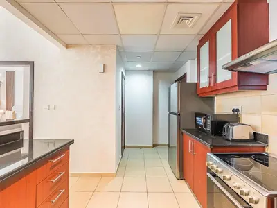 a kitchen with wooden cabinets and a stainless steel refrigerator at The Cozy Cove 1BR at Rimal 4,JBR in Dubai
