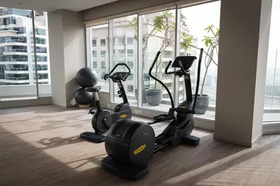 a gym with cardio machines in a room with windows at Gracious 1BR in Condor Marina Star, Dubai Marina in Dubai