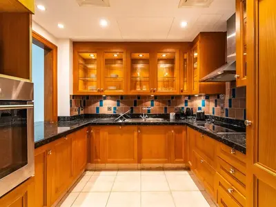 a kitchen with wooden cabinets and black counter tops at Cozy 1BR- Yansoon 4- Heart of Downtown Dubai in Dubai