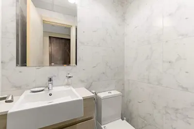 a white bathroom with a sink and a toilet at Silkhaus Signature 1BR in Afnan at Production City in Dubai