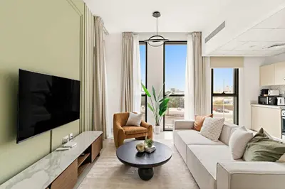 a living room with a white couch and a tv at Silkhaus Signature 1BR in Afnan at Production City in Dubai