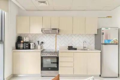 a kitchen with white cabinets and a refrigerator at Silkhaus Signature 1BR in Afnan at Production City in Dubai