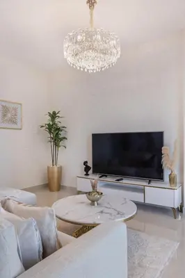 a living room with a large television and a chandelier at Classy 2BR Apt in Shams1 Panoramic view in JBR in Dubai