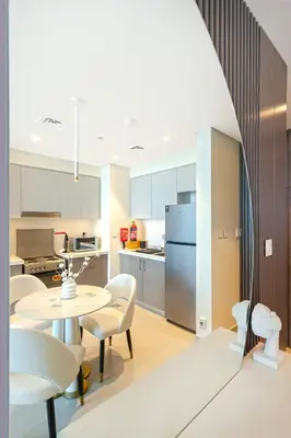 a kitchen with a table and chairs and a refrigerator at Sky-High Downtown 1BR Steps from Burj Khalifa in Dubai