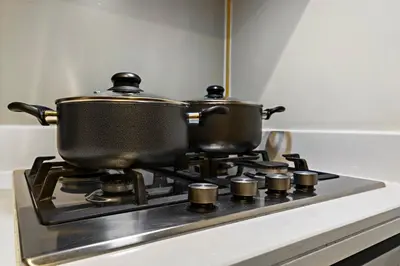 two pots on top of a stove in a kitchen at Sleek 1BR Apt with Pool Gym by Dubai Canal, Dubai Mall & Business Bay in Dubai