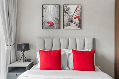 a bedroom with red pillows and three paintings on the wall at Sleek 1BR Apt with Pool Gym by Dubai Canal, Dubai Mall & Business Bay in Dubai