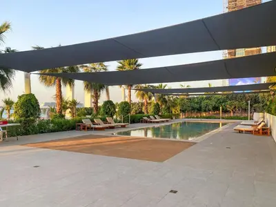 a patio with a pool and a large umbrella at Relaxing 1BR in Dubai With Access to Pool, Gym & Parking in Dubai