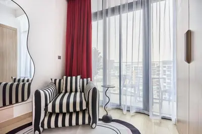 a living room with a chair and a red curtain at Elegant Cozy Stu Luxury Stay 10 Min Dubai Mall in Dubai