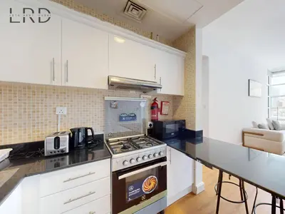 a kitchen with white cabinets and a stove top oven at Charming 1BR Apartment with Canal View in Business Bay in Dubai