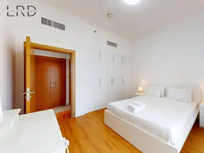 a white bedroom with two beds and a wooden floor at Charming 1BR Apartment with Canal View in Business Bay in Dubai